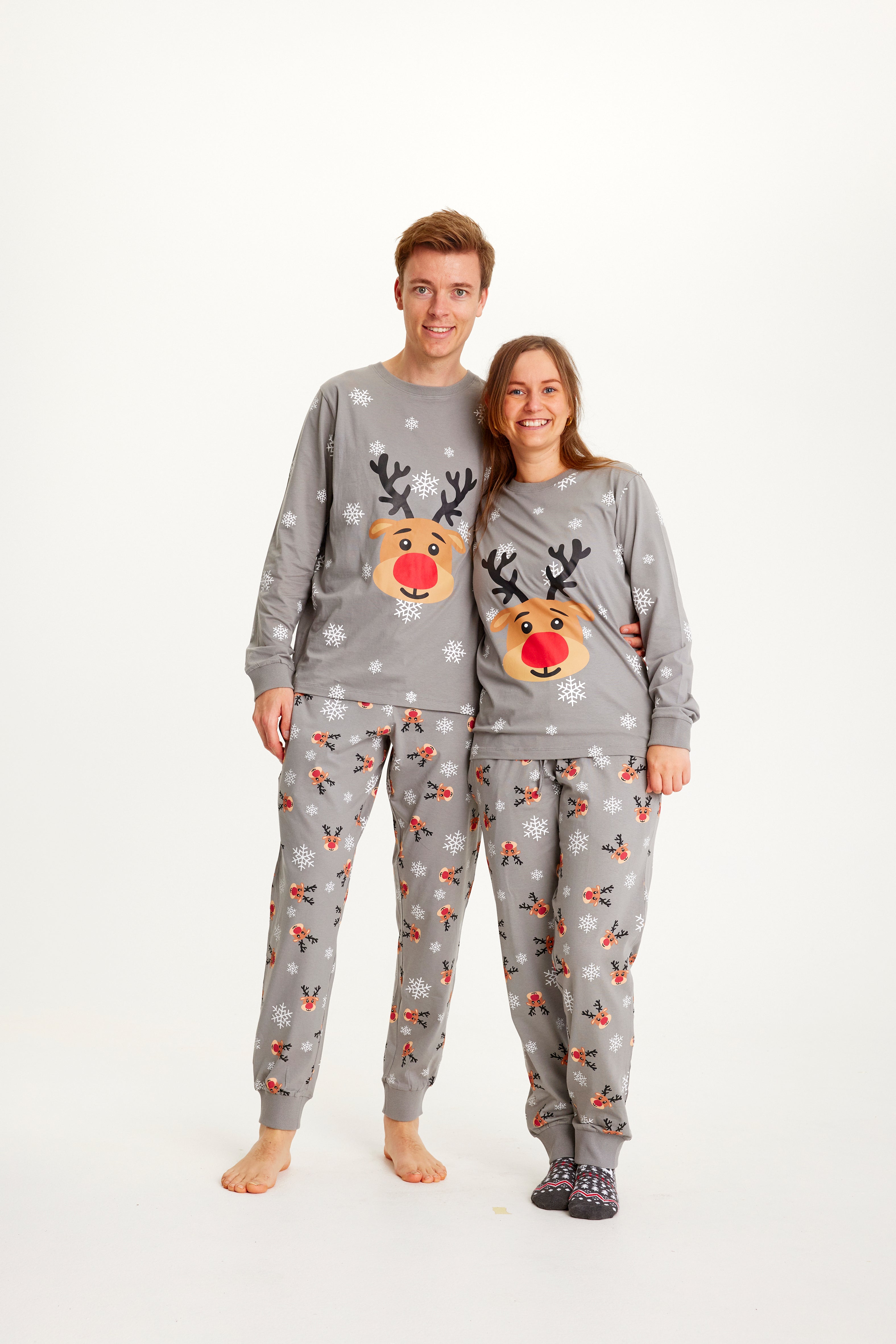 Ett par i grå julpyjamas med Rudolf och snöflingor.