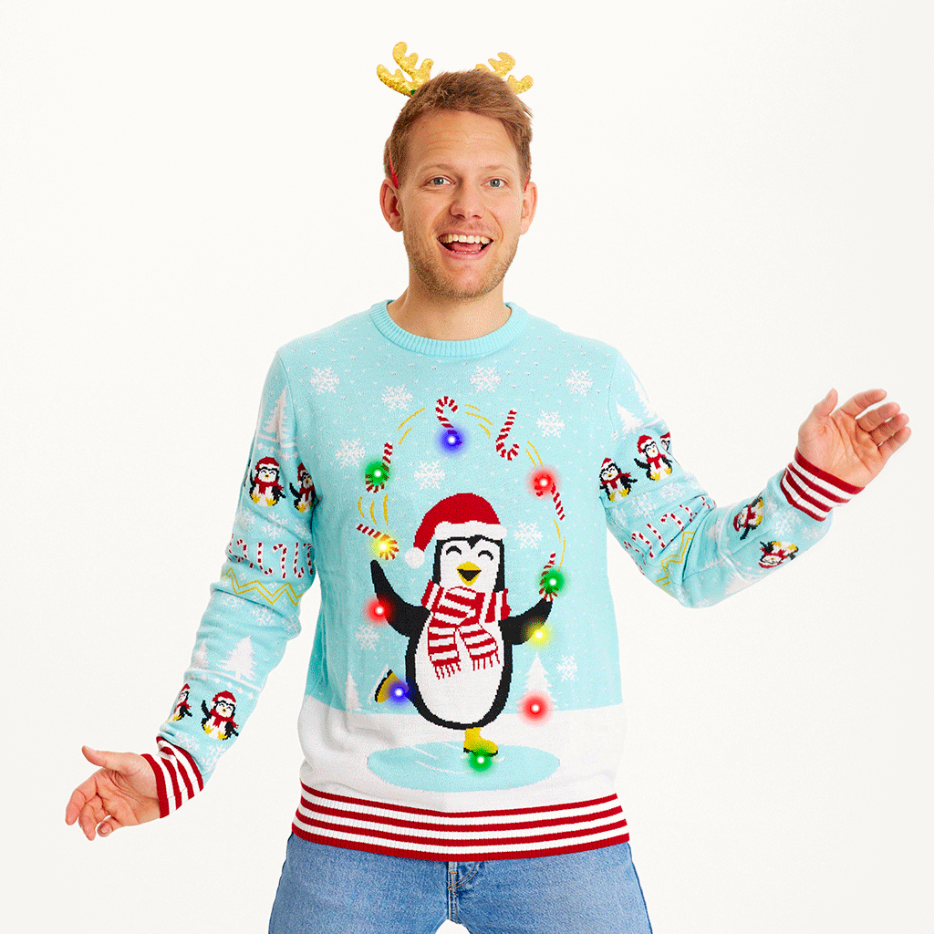 En man i en ljusblå jultröja med en pingvin och ljus.