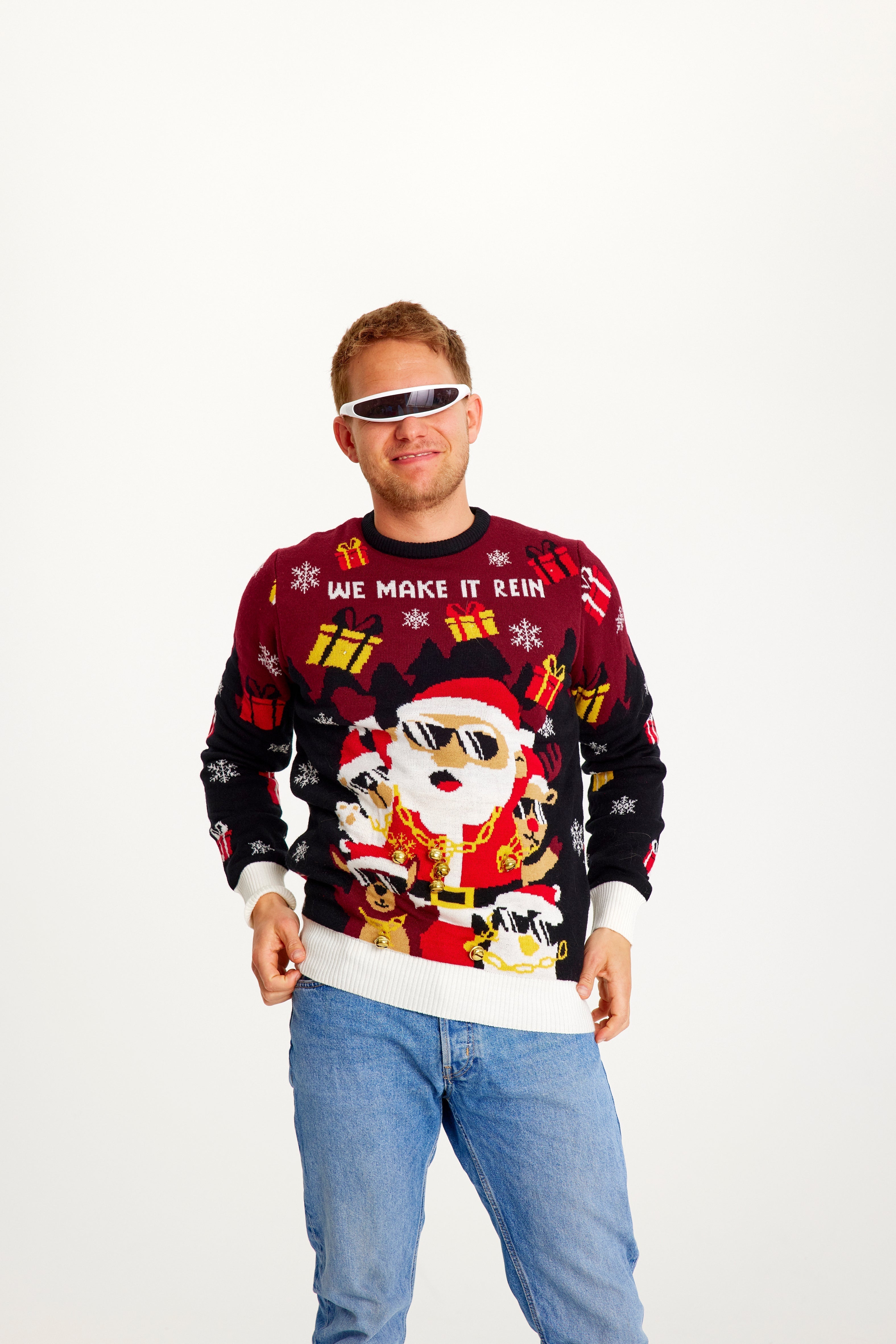 En leende man i röd och svart jultröja med en jultomte med solglasögon och tända lampor.