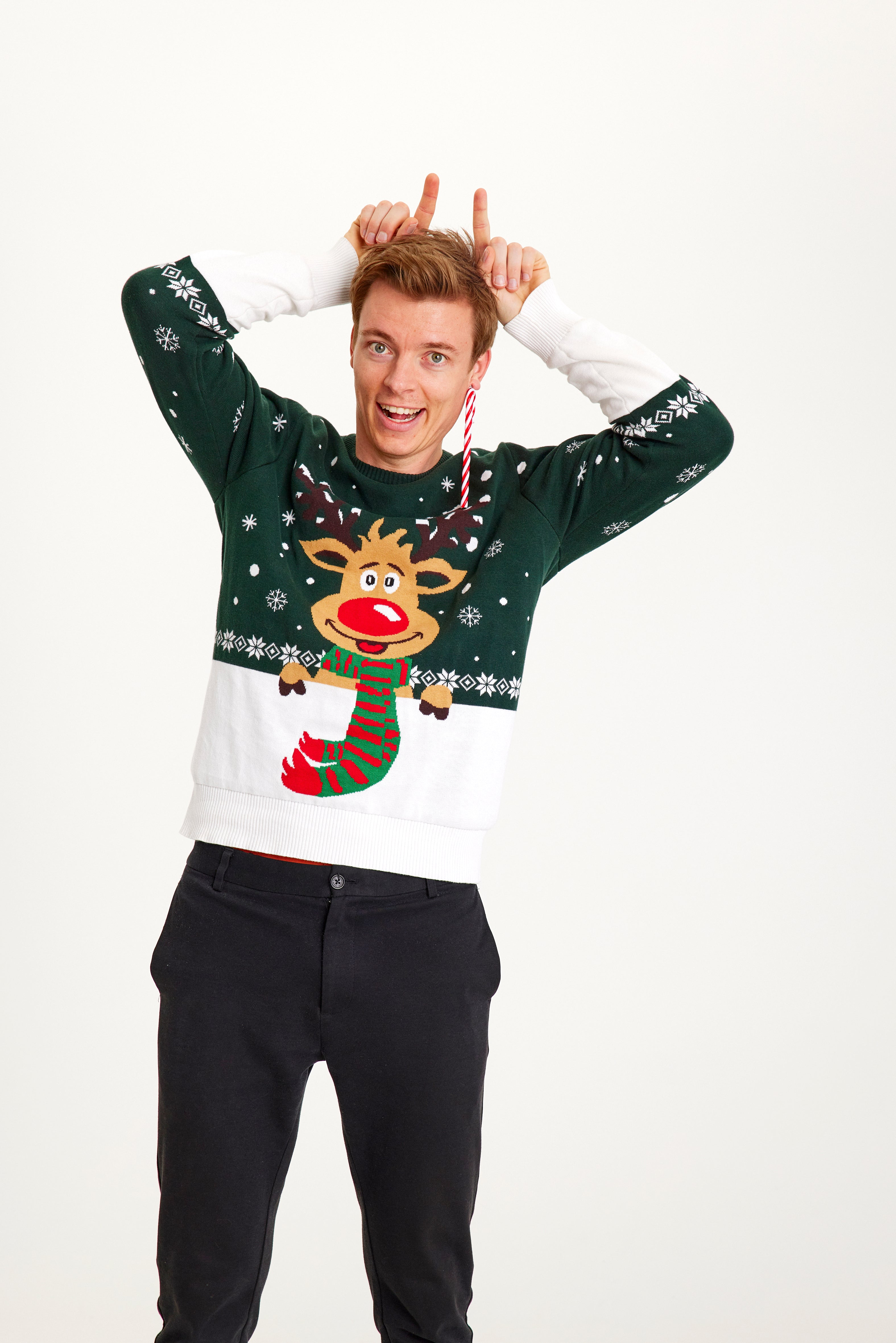 En poserande man i grönvit jultröja med Rudolf på.