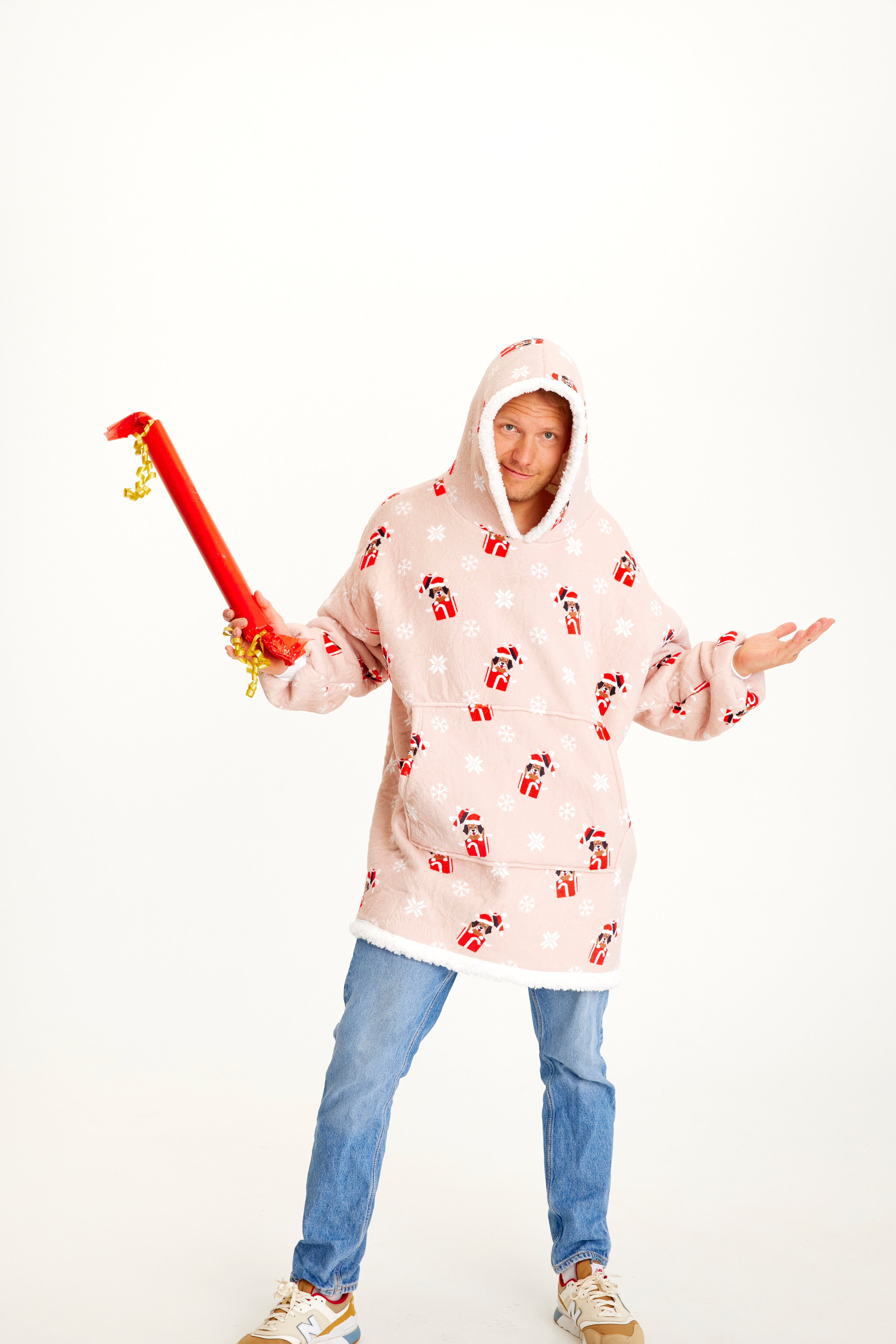 En man med en gåva som bär en rosa huvtröja med julhundar på.