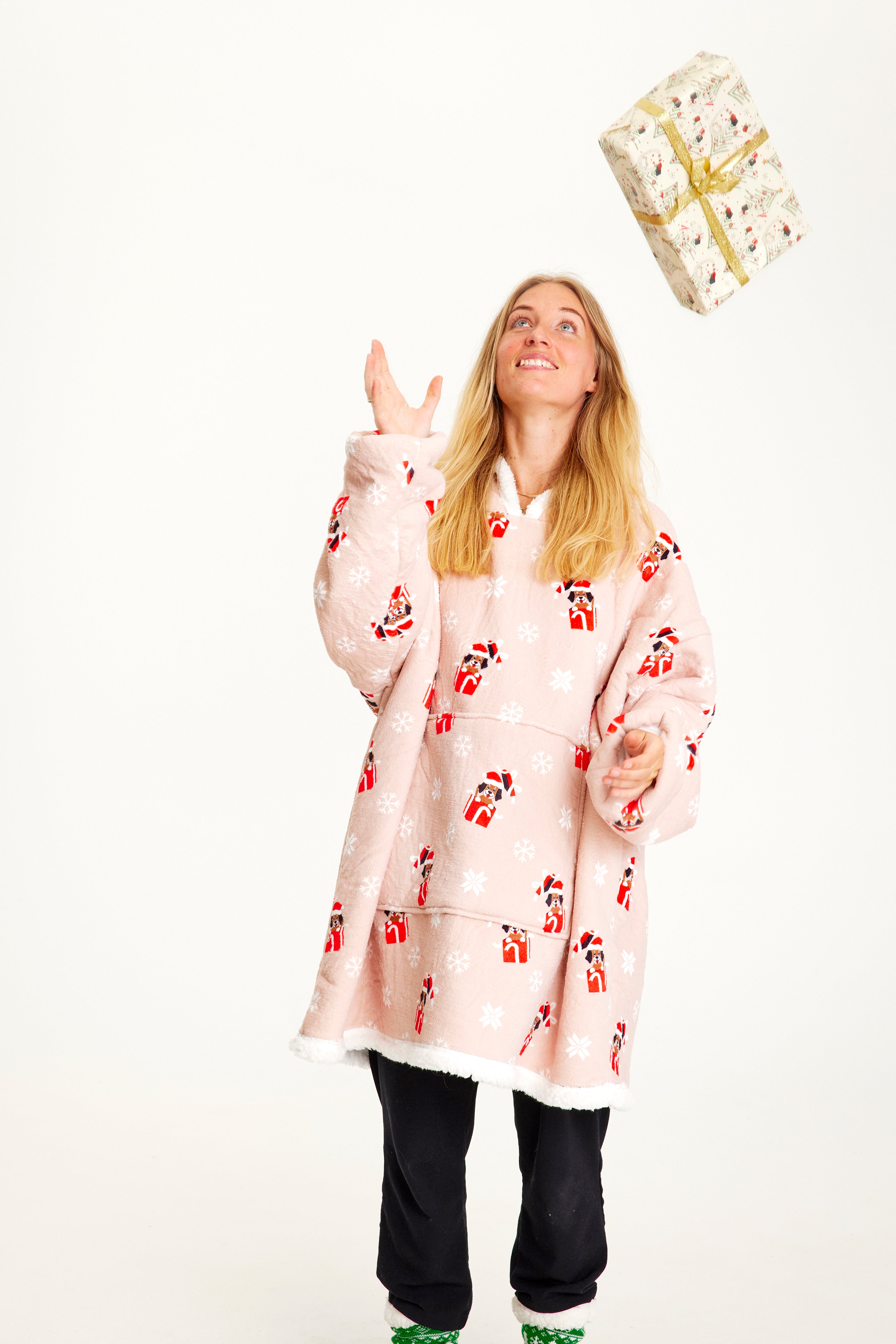 En kvinna som bär en rosa huvtröja med julhundar på.