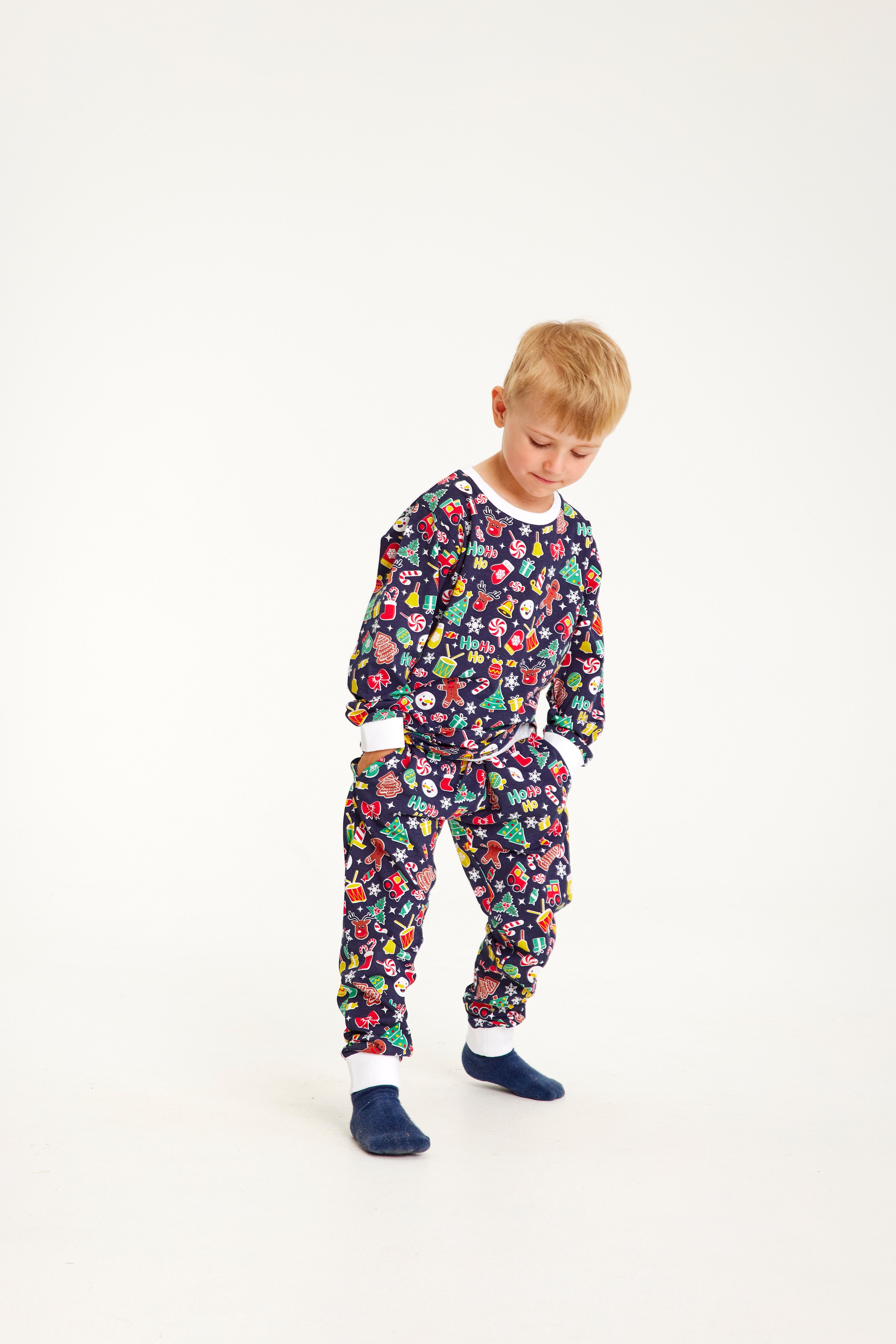 Ett sött litet barn i blå julpyjamas med julmönster.