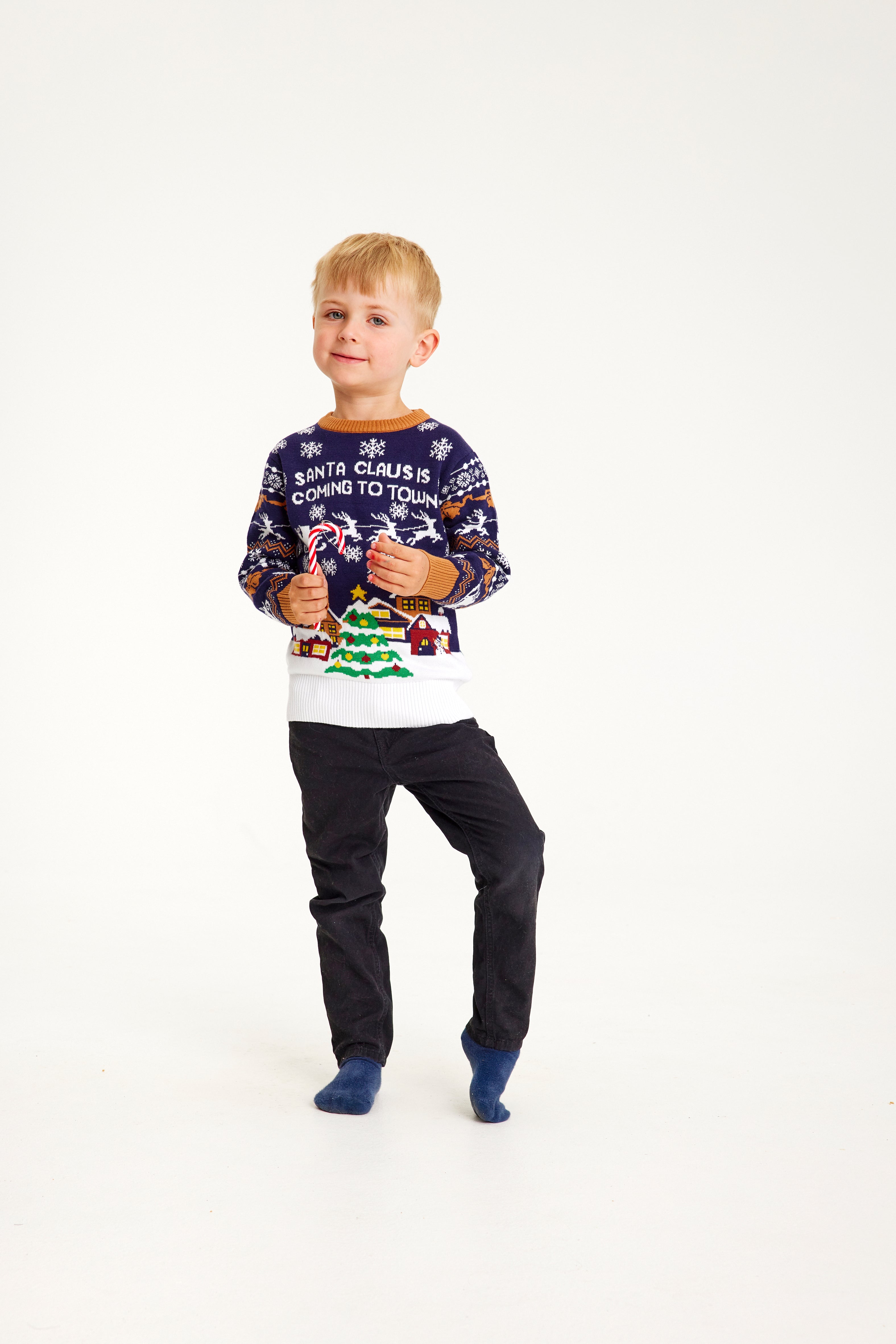 Ett leende barn i en blå jultröja med texten 