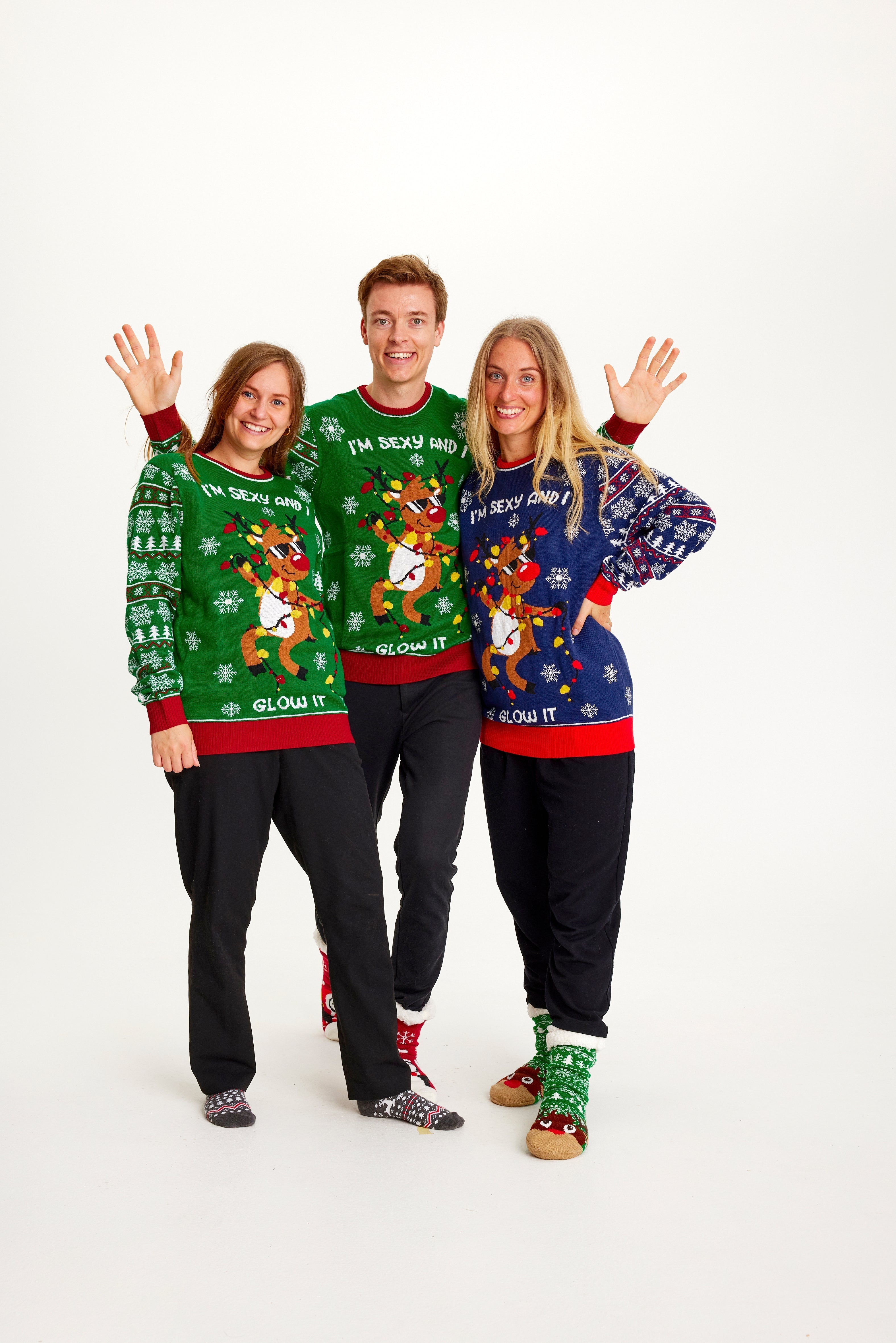 Tre personer i jultröja med dansande renar och ljus.
