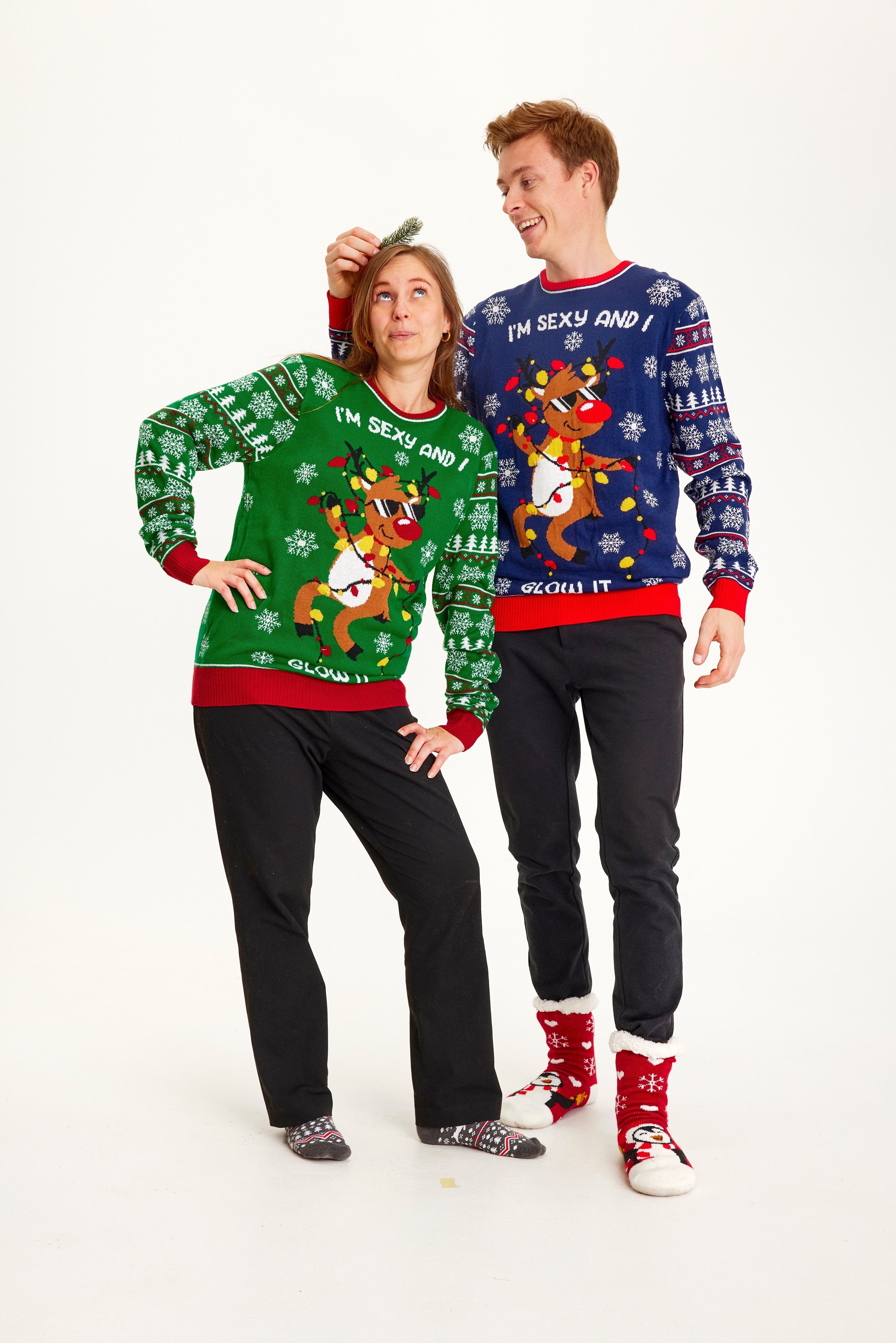 Ett par i jultröja med dansande renar och ljus.