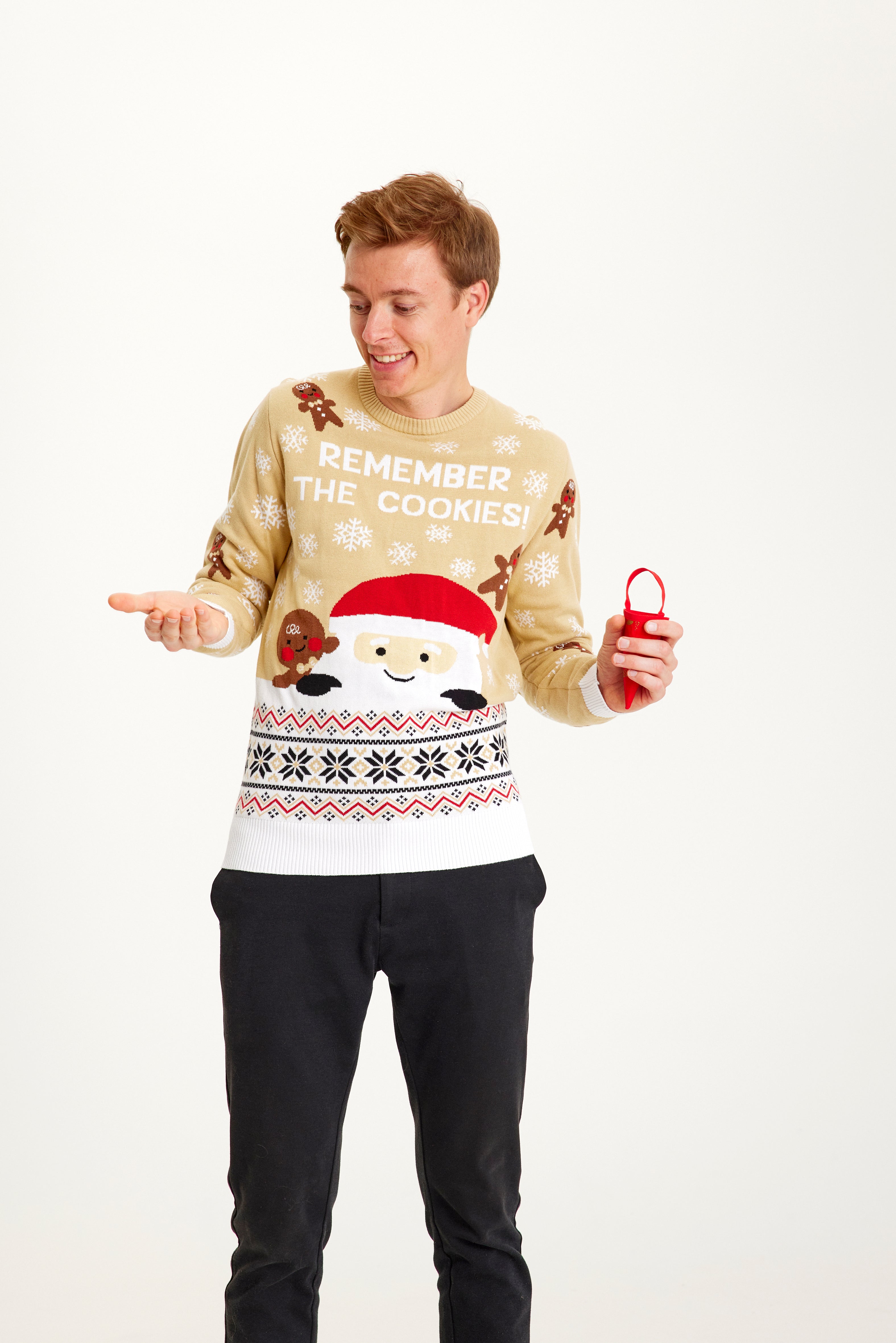 En man klädd i en beige jultröja med en tomte och kakgubbar på.