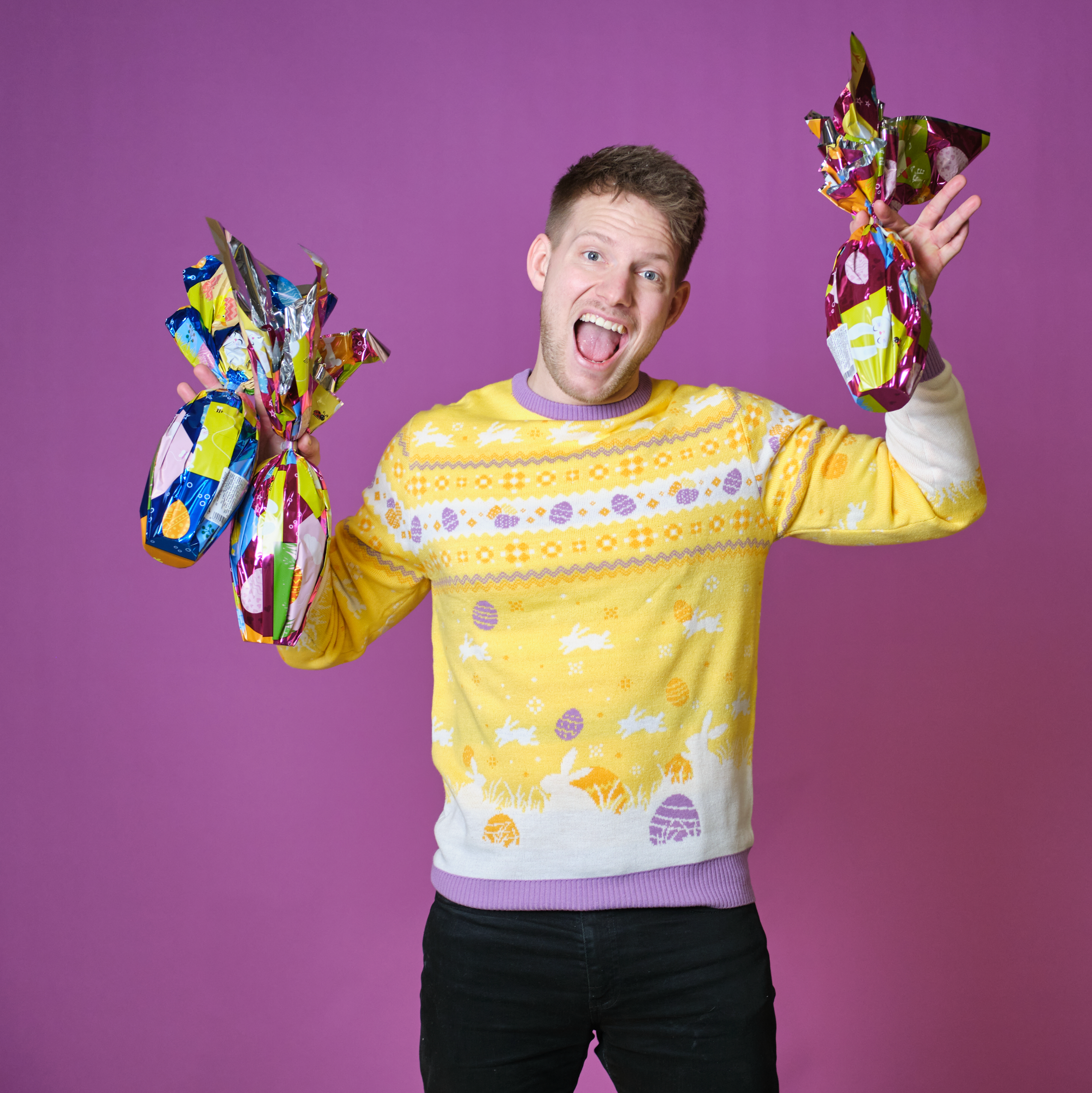 En man med chokladägg som bär en gul påsktröja med påskägg på.